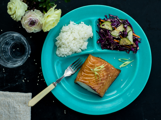 miso marinated sablefish on blue plate with cucumber salad and rice