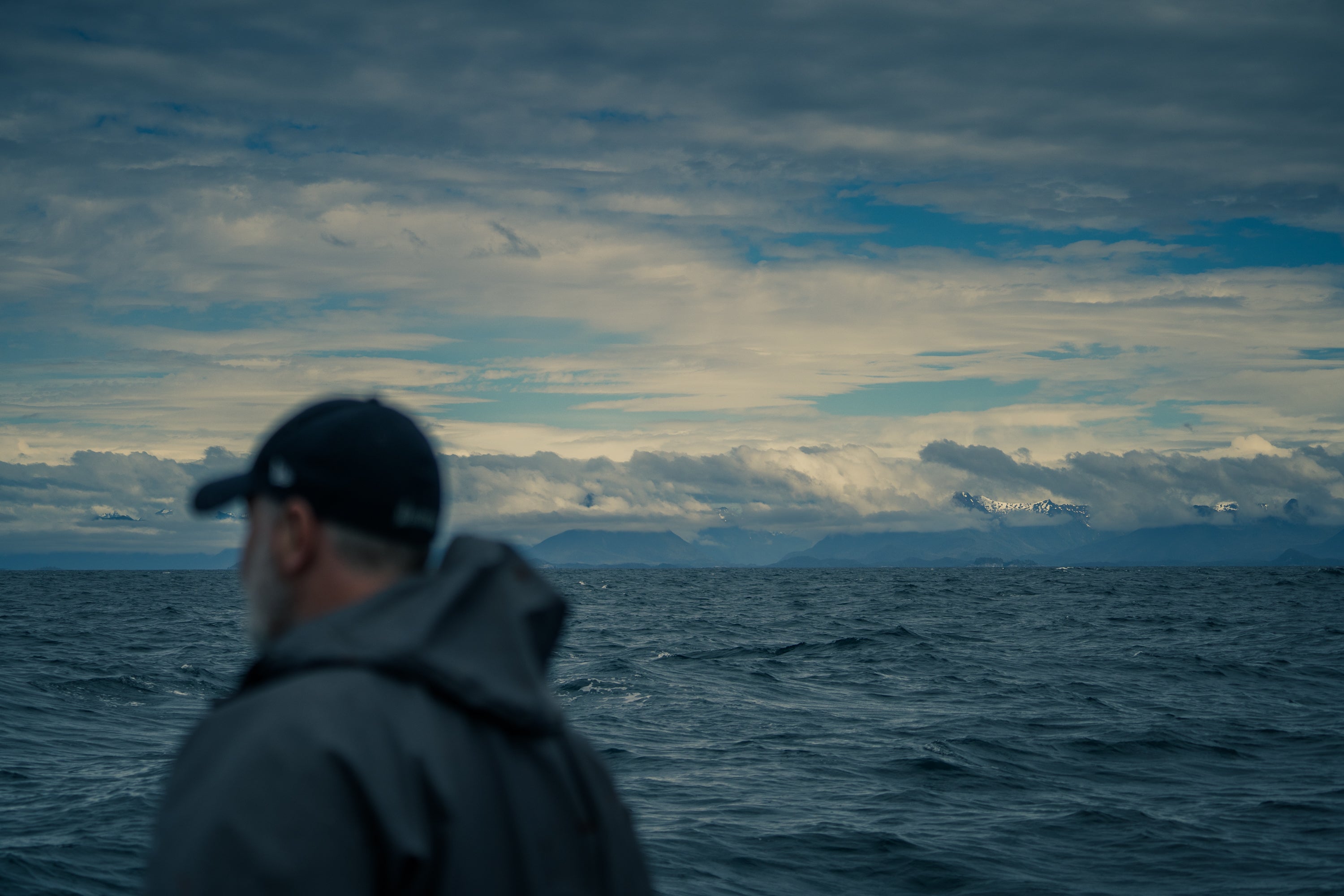 Fisherman on ocean looking at southeast Alaska mountain range