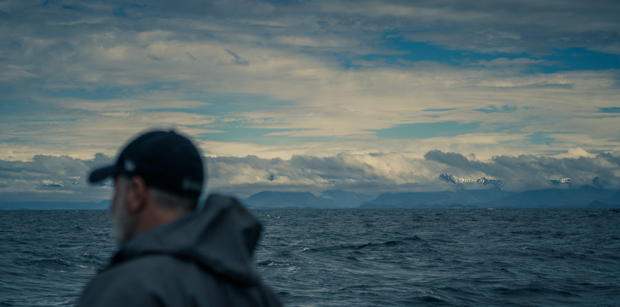 Fisherman on ocean looking at southeast Alaska mountain range