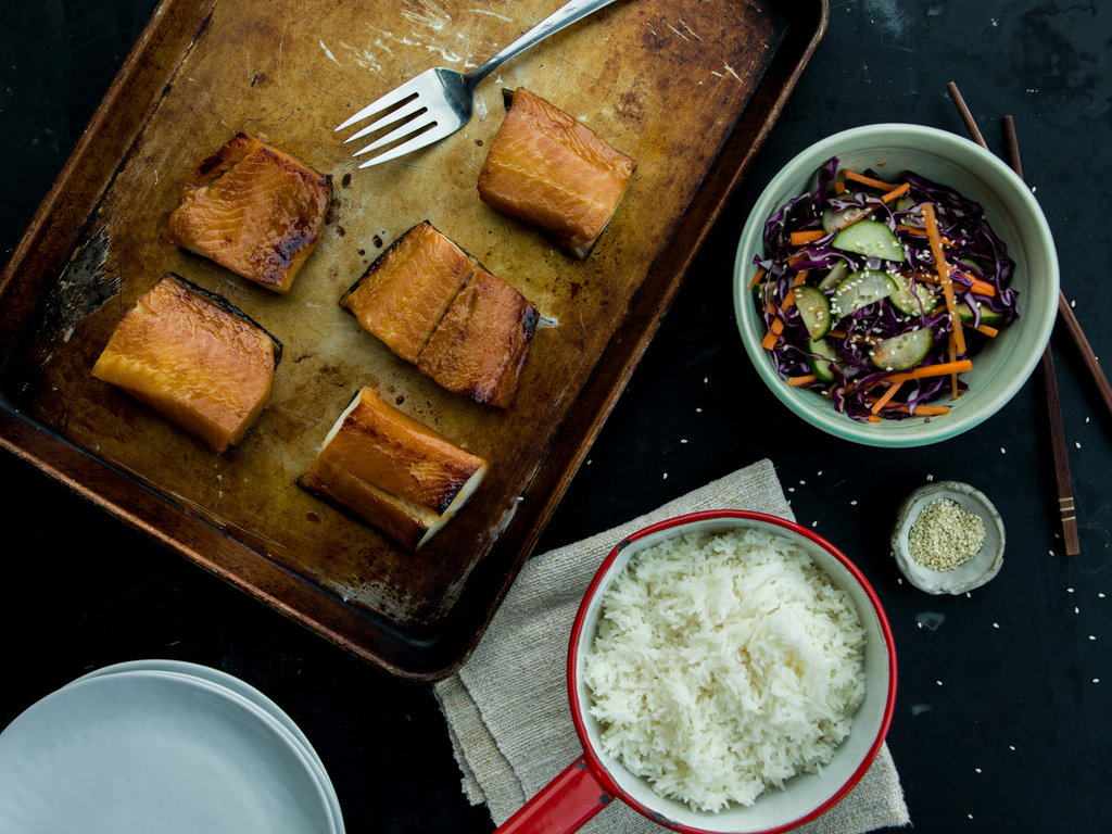 miso marinated black cod on baking sheet with cucumber salad and rice