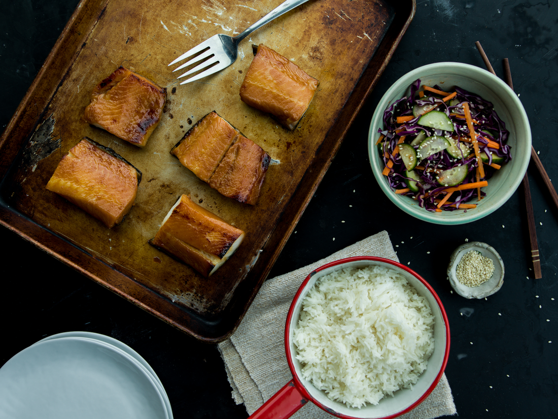 miso marinated black cod on baking sheet with cucumber salad and rice